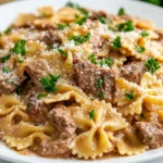 creamy beef and bowtie pasta served hot in a white bowl